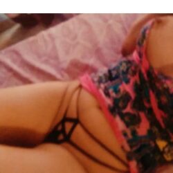 Person lying on a pink bed in a colorful, floral swimsuit with visible strap details.
