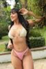 Smiling woman in a white bikini top and pink bottoms posing outdoors among greenery, with a gold VIP watermark across the image. Smiling woman in a white bikini top and pink bottoms posing outdoors among greenery, with a gold VIP watermark across the image.