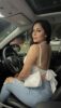 Woman posing in a car seat, wearing a white backless top and ripped jeans with a white purse over her shoulder, looking at the camera. Woman posing in a car seat, wearing a white backless top and ripped jeans with a white purse over her shoulder, looking at the camera.