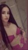 Selfie of a woman with long dark hair in a pink bikini, posing with a hand on her hip in a marble-tiled bathroom.