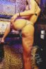 Back view of a woman in a bikini bottom, posing on a leopard-print backdrop/stage.