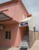 Pink two-story building with a blue 'Erotic Studio' sign above a gray outdoor staircase to the entrance.