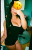 Woman taking a mirror selfie in a black sleeveless bodysuit; face obscured by a kiss emoji, long dark hair visible, tattoos on her thigh.