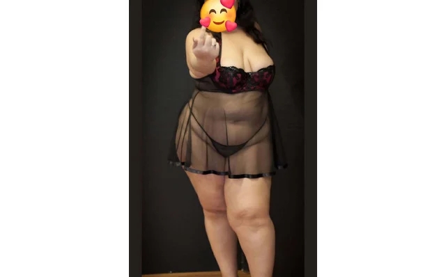 Person in sheer black lingerie with a robe, facing the camera and pointing; face covered by an emoji, standing in a doorway. Person in sheer black lingerie with a robe, facing the camera and pointing; face covered by an emoji, standing in a doorway.
